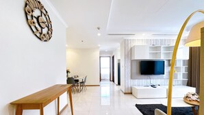 Un soggiorno moderno con un tavolo consolle in legno, una TV a parete e una zona pranzo sullo sfondo.