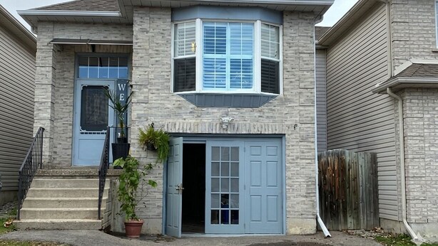 A two-story house with a front entrance, a bay window, and a garage door.