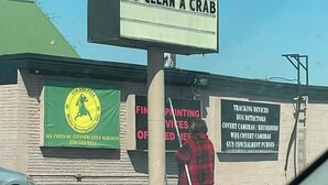 A signboard with a humorous message, a brick building, and a person cleaning. - Cozy 2-bedroom condo in lovely Land O' Lakes with AC (Land O' Lakes)