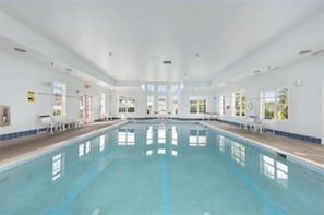 An indoor swimming pool with clear water, white walls, and a long, straight layout.