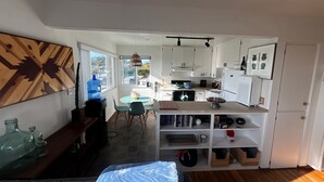 A compact living space with a kitchenette, dining area, and a bed.