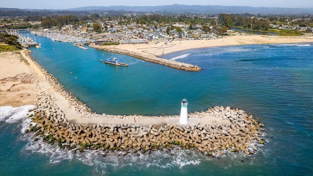 A coastal town with a lighthouse, marina, and beach.