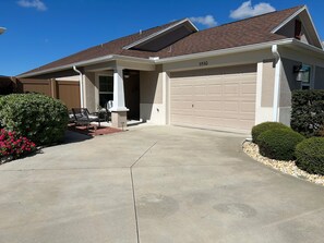 Ein Wohnhaus mit Garage, überdachter Veranda und Auffahrt.