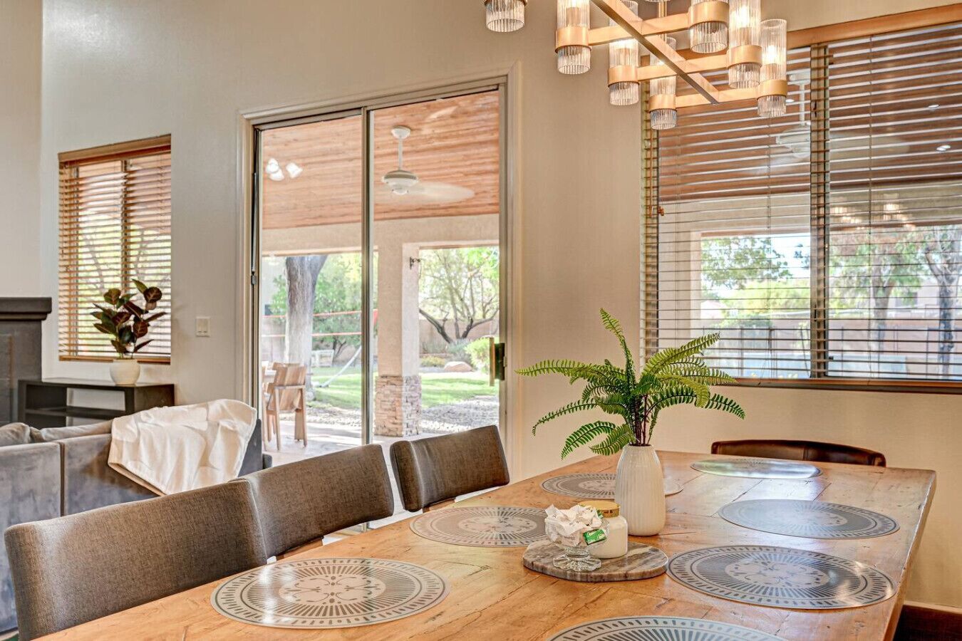 A dining area with a large table, chairs, a plant, and a ceiling fan.