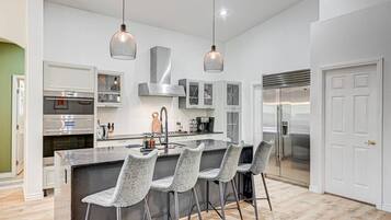 A modern kitchen with a central island, bar stools, stainless steel appliances, and pendant lighting.