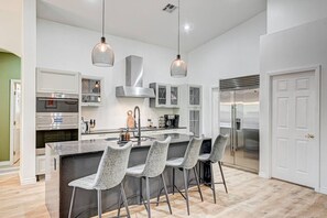 A modern kitchen with a central island, bar stools, stainless steel appliances, and pendant lighting. - Luxe 6Br Home Large 40ft Pool & Spa, Mini Golf, RV Parking (Las Vegas)