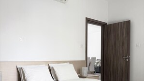 A hotel room with a bed, bedside table, lamp, and an air conditioning unit. - Luxury 2BR Apartment · 1 min to Beach (Larnaka)