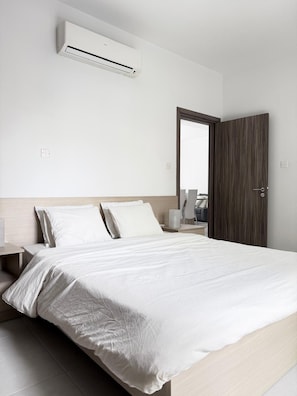 Une chambre d’hôtel équipée d’un lit, d’une table de chevet, d’une lampe et d’un appareil de climatisation.