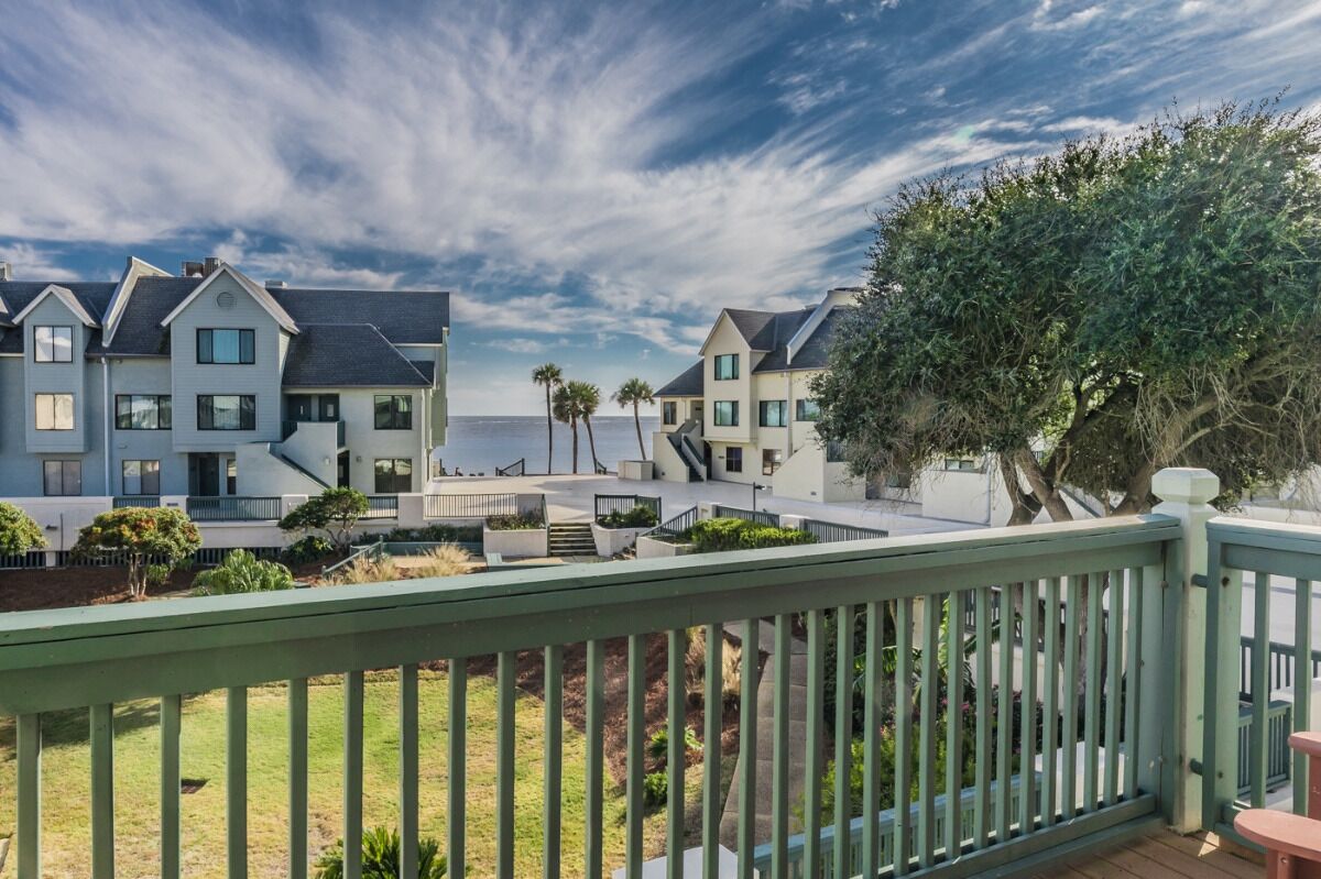 A coastal residential area with modern houses, a clear sky, and a view of the sea.