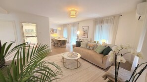 A living room with a sofa, coffee table, and a dining area in the background. - Townhouse in the Heart of Cascais Historic Center, 5 minutes walk from the beach (Cascais)