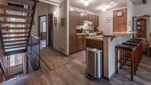 A kitchen with wooden cabinets, a stainless steel sink, and a bar area with stools. - Family-Friendly Retro Townhouse 1 Mile from Lake (Kings Beach)
