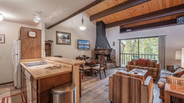 A kitchen with a wooden island, dining area with chairs, a fireplace, and a balcony with outdoor seating. - Family-Friendly Retro Townhouse 1 Mile from Lake (Kings Beach)