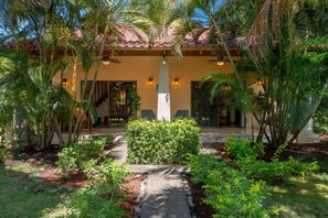 A resort with a palm tree-lined entrance, a pathway leading to the building, and a well-maintained garden.