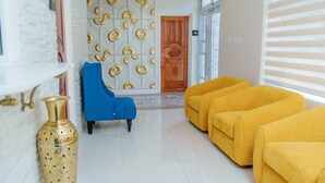 A modern interior with a white brick wall, a blue armchair, and a row of yellow sofas. - Royale Jazz Hotel  (Kingston)