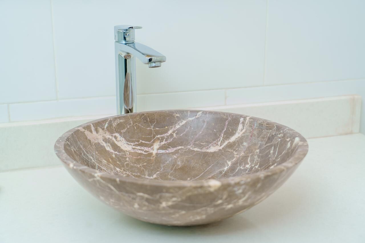 A bathroom with a marble sink and a chrome faucet.