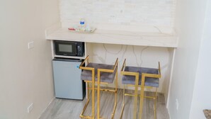 A compact kitchenette with a microwave, a small refrigerator, and a white countertop. - Royale Jazz Hotel  (Kingston)