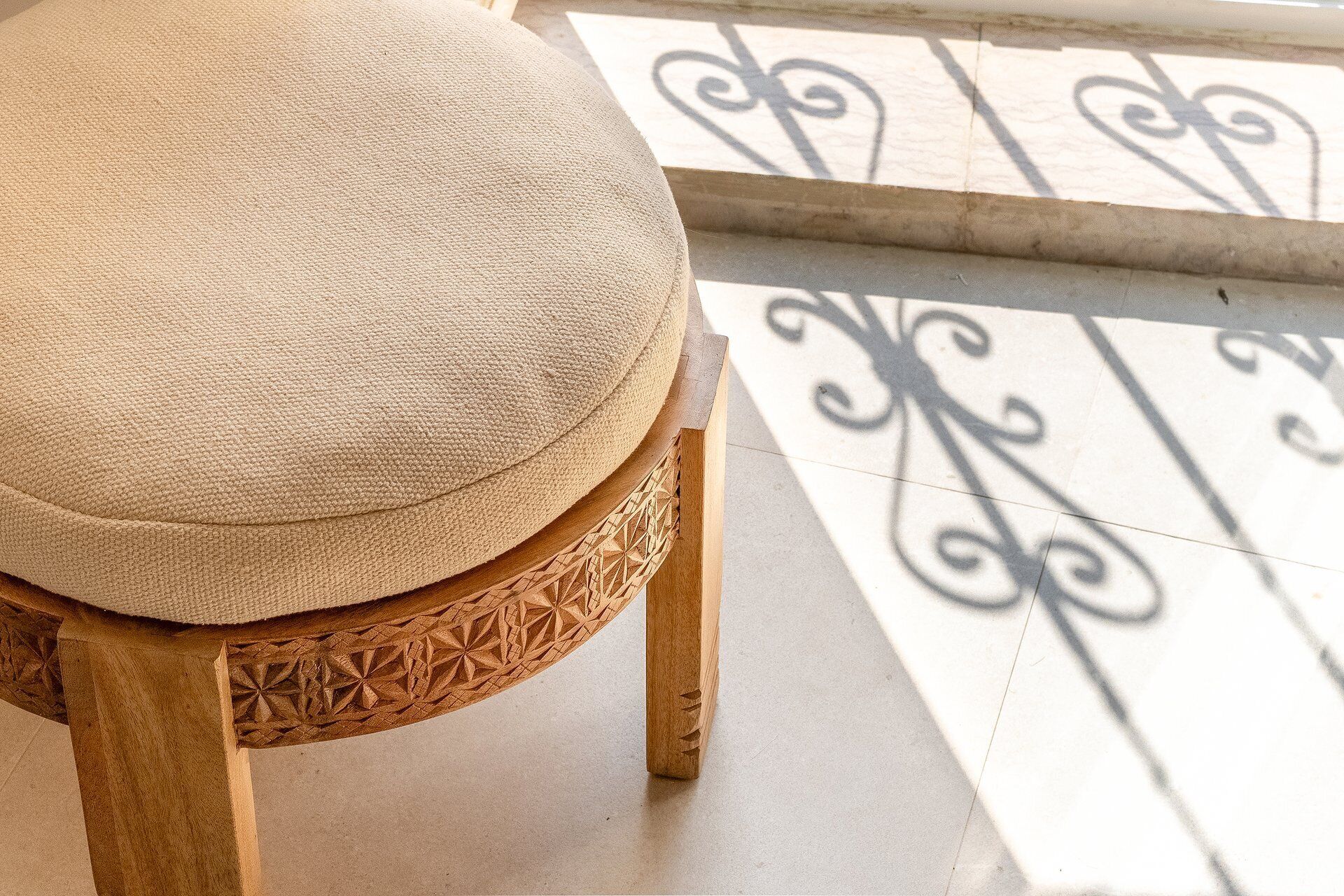 A wooden stool with a textured cushion.
