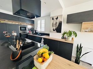 A modern kitchen with a central island, a microwave, and a stove. There is a basket of fruit on the island and a potted plant on the counter. - Marina with magnificent view of the lake 3bed- 2 parkings - wifi (Aigues-Mortes)