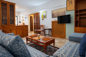 A living room with a sofa, coffee table, wooden cabinets, and a television. - Sunny Terrace Sea View Apt in Piraeus by ΜΡS (Pireas)