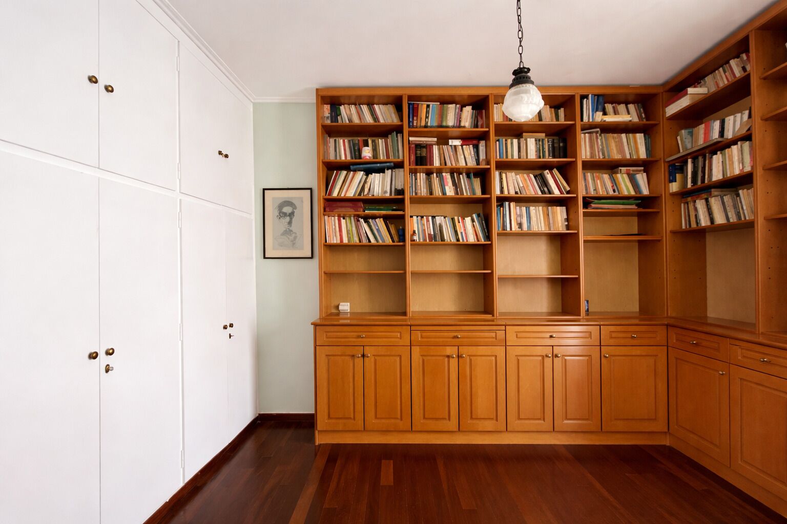 A room with a wooden cabinet, a bookshelf, and a framed picture on the wall.