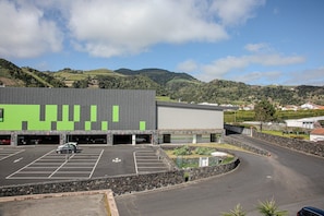 A parking lot with a building featuring a green facade and a stone wall.