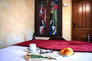 A bed with a red blanket, a cup, a plate with croissants, and a book with glasses on it. - Medieval Country House Senorio de Montero (Cenizate)