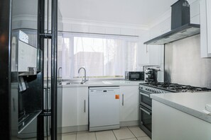 A modern kitchen with a dishwasher, microwave, stove, and oven. - The Retreat (Deal)