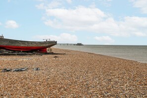 Ein Kiesstrand mit einem Boot und einer Mole im Hintergrund.