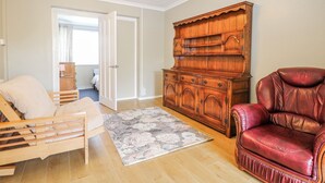 A room with a wooden bed, a red leather chair, a wooden cabinet, and a door leading to another room. - The Retreat (Deal)