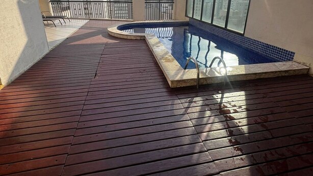 A rooftop swimming pool with a wooden deck, a view of the city, and a clear sky. - Flat em Moema com Cozinha (São Paulo)