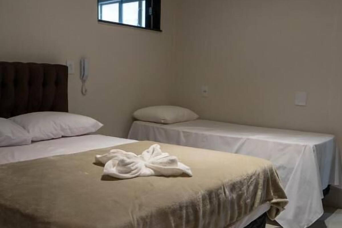 Een hotelkamer met een groot bed, een kleiner bed, een raam en een airconditioning.