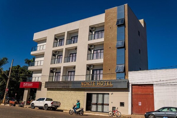 Un hotel de varios pisos con balcones, un letrero que dice 'Norte Hotel' y un restaurante 'D'Gust' al otro lado de la calle.