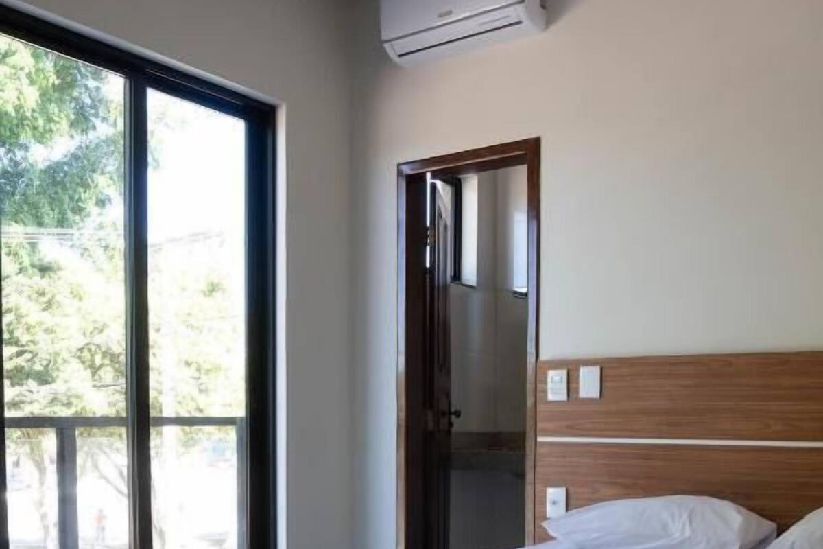 Een hotelkamer met een bed, een groot raam en een airconditioning.