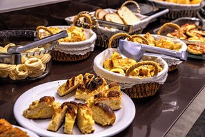 Un bufé con diversas opciones de panadería, incluyendo pan, pasteles y muffins.