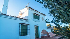 Un edificio bianco con tetto in tegole, una porta verde e una finestra con inferriate.