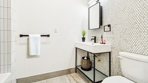A bathroom with a white sink, a mirror, a toilet, and a towel rack. - Two Bedroom - Newly Renovated - Washer/Dryer in New York City (New York)
