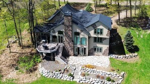 Una casa de varios pisos con fachada de piedra, un porche cubierto y un camino de piedra que conduce a la entrada.