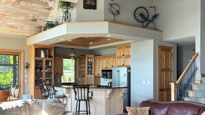 Un amplio espacio habitable con techo de madera, una cocina con armarios de madera, un comedor y una escalera.
