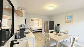 Een compacte hotelkamer met kitchenette, een bed, een eethoek en een kleine zithoek.
