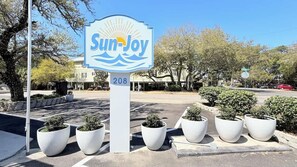 A Sun-Joy hotel sign with a number 208, surrounded by potted plants. - Sun-Joy Stay #10 | 5-Min Walk to Beach (Myrtle Beach)