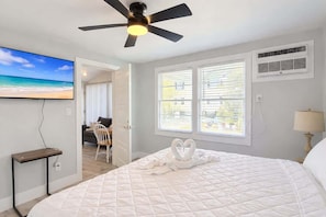 A bedroom with a bed, a ceiling fan, a TV, and a window with blinds. - Sun-Joy Suite #3, Central MB | 5 min Walk to Beach (Myrtle Beach)