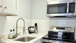 Una cucina moderna con mobili bianchi, un forno in acciaio inossidabile, un microonde e un lavello con un rubinetto.