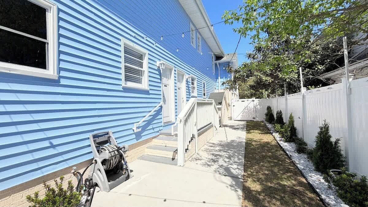 A blue house with a white fence, a small staircase, and a bicycle.