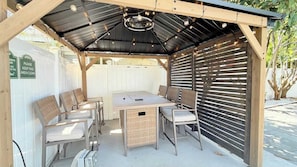 A covered patio with a table and chairs, a ceiling light fixture, and a sign indicating the area is to be kept clean. - Sun-Joy Suite #7 | Walk to Ocean, Myrtle Beach (Myrtle Beach)