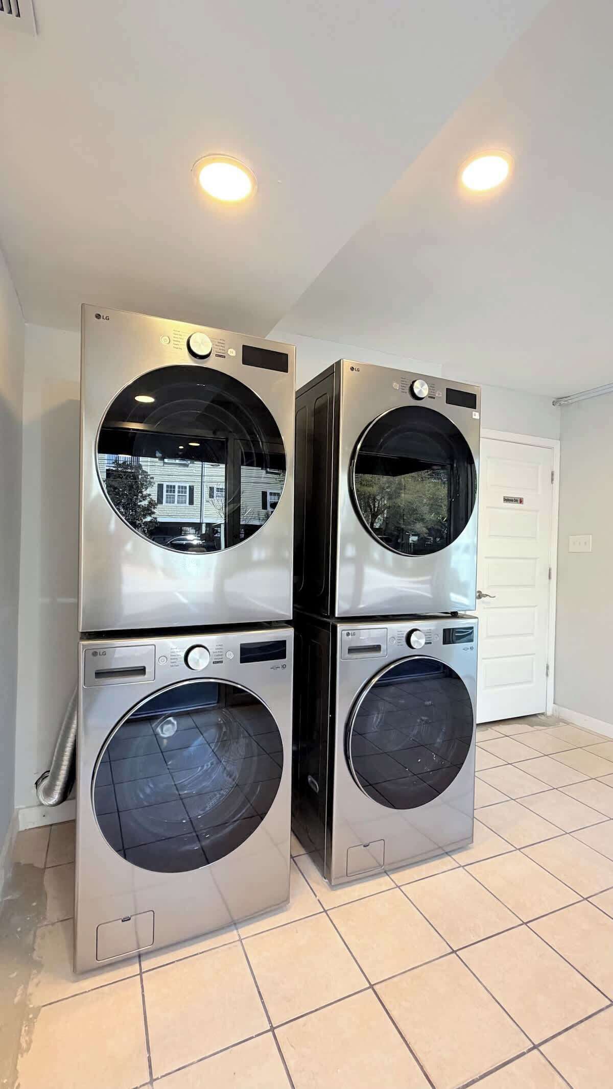 A laundry room with two stacked LG front-loading washing machines and a white door in the background.