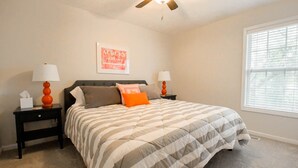 A bedroom with a bed, two nightstands, a ceiling fan, a window with blinds, and a wall-mounted picture. - Saturdays on Donahue (Auburn)