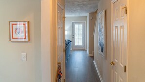 A hallway with doors, a light switch, and a framed picture on the wall. - Saturdays on Donahue (Auburn)