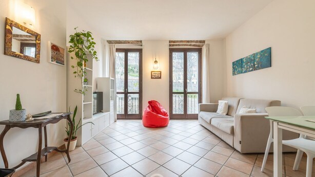 Ein Wohnzimmer mit einer Couch, einem Sitzsack, einem Esstisch und einer Topfpflanze.