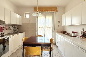Una cucina con mobili bianchi, un tavolo da pranzo in legno e sedie gialle.
