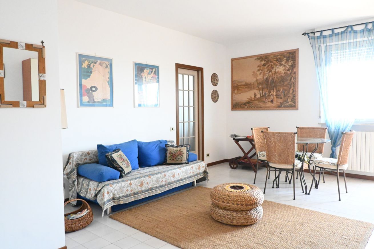 A living room with a sofa, chairs, a table, a large painting, and a mirror.